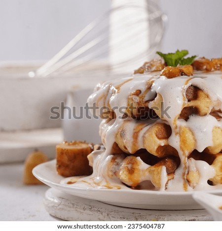 stacked pancake waffles, close-up photo, drizzled with delicious cream sauce and banana caramel, on a white plate. selected focus.