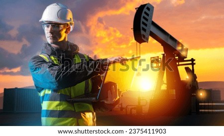 Oil worker man with laptop. Petroleum fields at sunset. Oil worker in protective helmet looks to side. Pumps for petroleum extraction. Fuel market. Man develops oil field. Fuel industry specialist Royalty-Free Stock Photo #2375411903