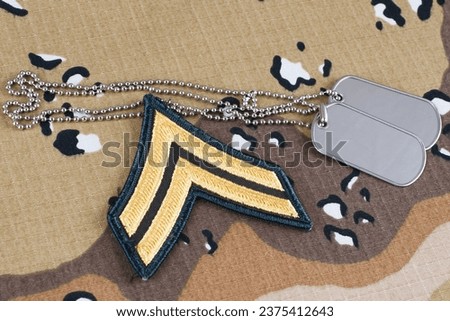 US ARMY Corporal rank patch and dog tags on desert camouflage uniform background