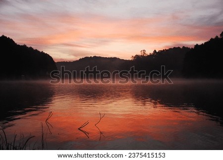 The stunning morning sunlight graces a large northern Thai reservoir, where tourists come to rejuvenate, replenishing both their physical and emotional energy, ready to face life’s challenges anew. Royalty-Free Stock Photo #2375415153