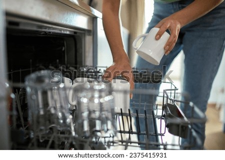 Close-Up of a young woman emptying her dish washer in the kitchen Royalty-Free Stock Photo #2375415931