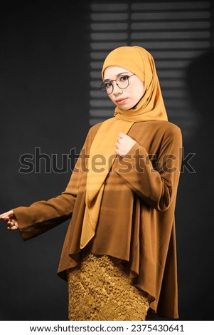 Cute women in yellow dress and hijab over studio background.