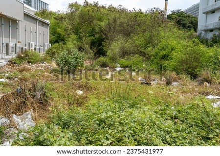 Garbage that is lying on the lawn and in the bushes in the vacant lot between the buildings. Environmental pollution with plastic waste. Environmental problem all over the world. Royalty-Free Stock Photo #2375431977