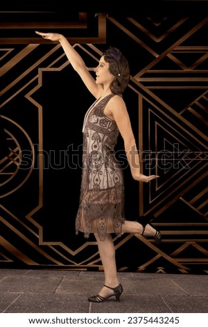 Vintage style photo of a woman dressed in a 1920's dress against an art deco background dancing.