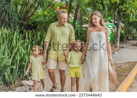 A joyful family, two girls, dad, and a pregnant mom, bask in tropical resort, celebrating a radiant pregnancy amidst paradise