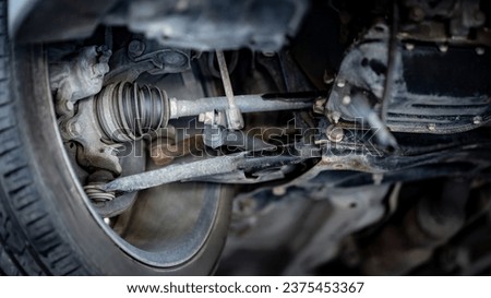 Drive shaft assembly or CV joint axle and wheel. Bottom view of car suspension. Old car on hydraulic lift during maintenance in auto repair shop Royalty-Free Stock Photo #2375453367