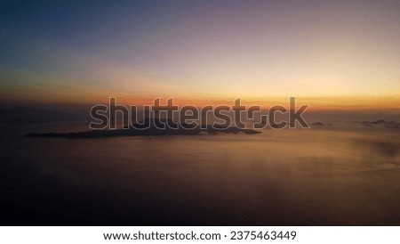 Tropical sunrise over an island in the ocean. Aerial view of an island in the sea at sunrise.