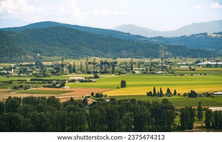 Beautiful farm landscape. The fertile farmland of the Fraser Valley in British Columbia south of the Fraser River. Summer in the Fraser Valley. Travel photo, copyspace Royalty-Free Stock Photo #2375474313