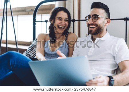 Couple having fun while sitting on bed and using laptop