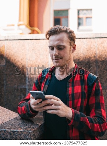 Young hipster walking in city with cellphone