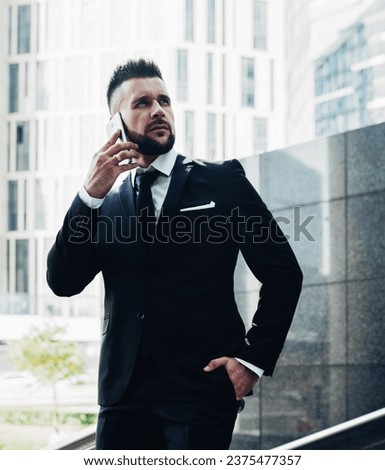 Young formal male speaking on phone standing on street