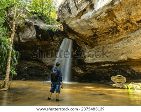 tourist Visit Saeng Chan Waterfall in the deep humid forest of Ubon Ratchathani, Thailand. Motion blurred leaves on slow shutter. Royalty-Free Stock Photo #2375483139
