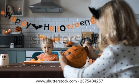Cute baby girl with older sister preparing for Halloween party in the kitchen