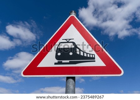 Triangular railway crossing sign in the blue sky