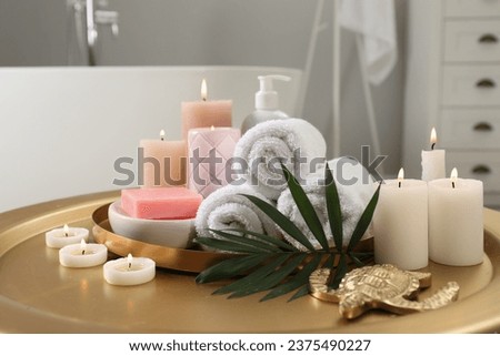 Composition with different spa products, burning candles and palm leaf on table in bathroom