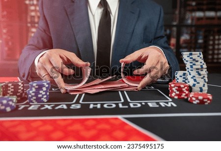 Man croupier holding playing cards before start game poker at casino. Texas holdem, gambling concept Royalty-Free Stock Photo #2375495175