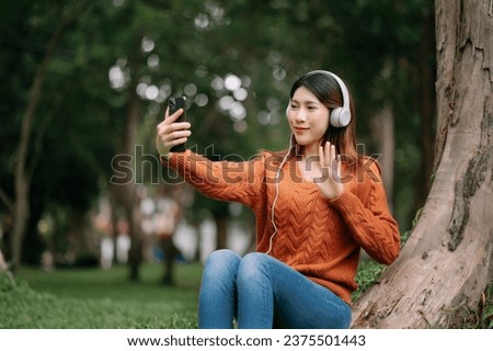 Beautiful young asian woman listening to music with headphone with feeling happy and relaxed, fresh with smiley face. in the park in morning