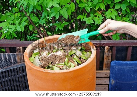 Green Shovel preparing organic fertilizer to home made compost bin in the garden with food leftover leaves stock photo copy space