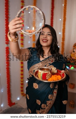 Traditional Indian women celebrating the festival of Karwachawth. Beautiful wife happily looking at the moon and then at her husband through a sieve - Karwa Chauth rituals, beautiful background
