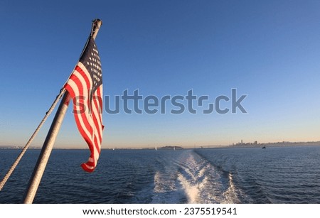 American flag. American flag flying against blue sky. Image captured in the back of a ferry boat. 