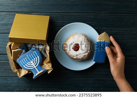 Box with gingerbread, donut and hand on wooden background, top view