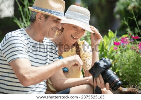cheerful senior tourist couple viewing pictures on camera