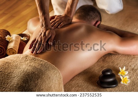 Deep tissue massage. Spa setup - stones, frangipani flowers and towels. Royalty-Free Stock Photo #237552535