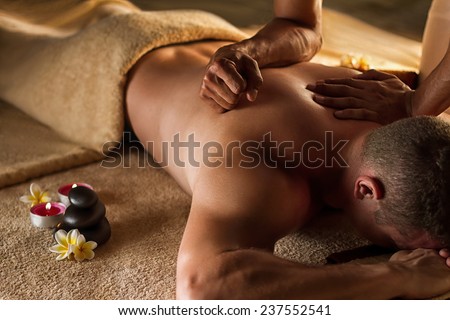 Deep tissue massage. Spa setup - stones, frangipani flowers and towels. Royalty-Free Stock Photo #237552541