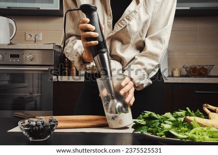 Hands of unrecognizable woman using blender to make smoothie Royalty-Free Stock Photo #2375525531