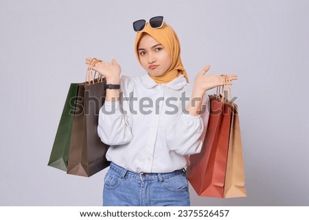 Pensive young Asian shopaholic Woman carrying shopping bags isolated on white background. online mobile shopping concept Royalty-Free Stock Photo #2375526457