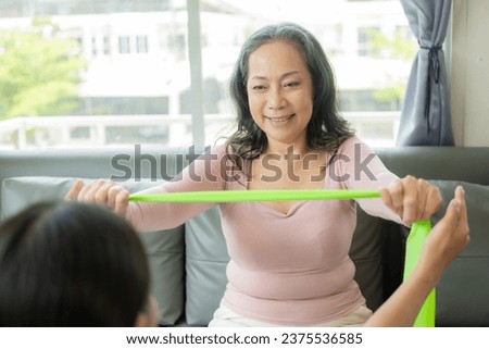 Elderly female patient with Asian female physical therapist holding her arm for physical therapy Rehabilitate weak muscles. A patient appears intent on doing this exercise in a hospital examination ro