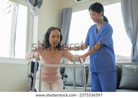 Elderly female patient with Asian female physical therapist holding her arm for physical therapy Rehabilitate weak muscles. A patient appears intent on doing this exercise in a hospital examination ro