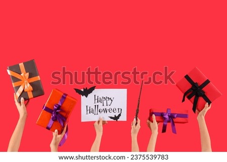 Women with Halloween gifts, card and wand on red background