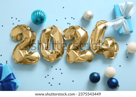 Figure 2024 made of balloons with Christmas gifts and decor on blue background