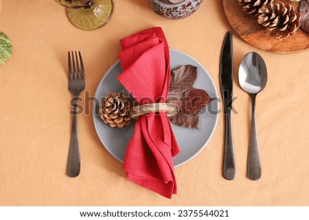 Autumn table setting with folded napkin, dry leaf and pine cone, closeup