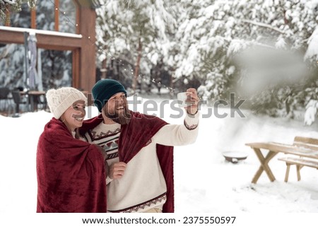 Caucasian couple making selfie in front of house in winter season 
