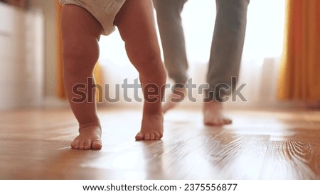 baby first steps. happy family kid dream concept. father teaches baby daughter to take first steps at home in front of window. lifestyle father's day concept. baby takes his first steps Royalty-Free Stock Photo #2375556877