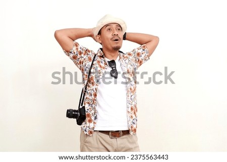 Happy relaxed asian adult man tourist standing while looking above. Concept of travel. Isolated on white background