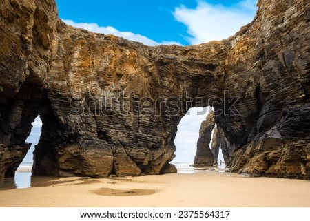 Natural rock arches Cathedrals beach, Playa de las Catedrales at Ribadeo, Galicia, Spain. Famous beach in Northern Spain Atlantic. Natural rock arch on Cathedrals beach in low tide Royalty-Free Stock Photo #2375564317