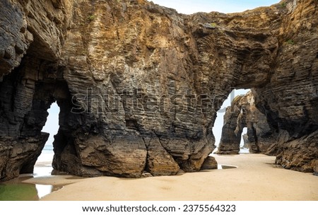 Natural rock arches Cathedrals beach, Playa de las Catedrales at Ribadeo, Galicia, Spain. Famous beach in Northern Spain Atlantic. Natural rock arch on Cathedrals beach in low tide Royalty-Free Stock Photo #2375564323