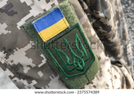 Close-up texture pixel camouflage military uniform of the Armed Forces, chevron trident and flag of Ukraine