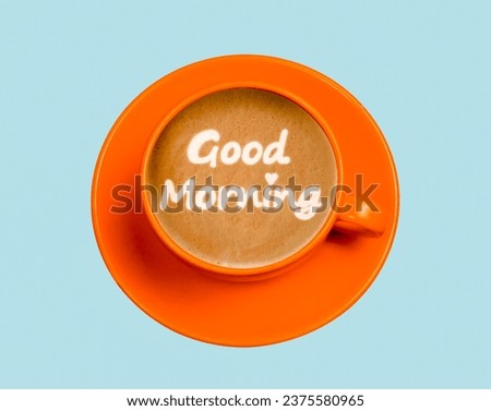 Top view orange cup with coffee and text good morning  made from milk foam on blue background. Minimal card idea. 