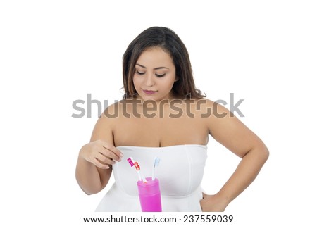 Beautiful young woman choosing a toothbrush against a white background