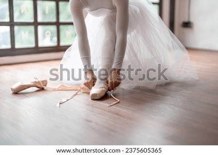 Ballerina in ballet shoes. Asian girl tying ribbons of toe shoes. ballet dancer preparing and wearing ballet shoes in dance studio prepares for a rehearsal