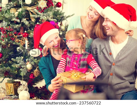 Christmas Family with Kids opening Christmas gifts. Happy Smiling Parents and Children at Home Celebrating New Year. Christmas Tree. Christmas scene 