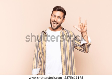 young man feeling happy, fun, confident, positive and rebellious, making rock or heavy metal sign with hand