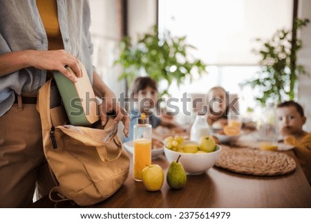 Mother packing school snacks for her children into school bag. Snack, school lunch in a snack box for school. Royalty-Free Stock Photo #2375614979