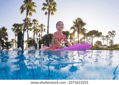 Girl floats on pink inflatable in the pool. Beach resort vacation by the sea. Winter and summer seaside resort holidays. Over-under underwater photography.