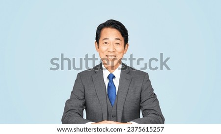 An middle-aged Asian man in a suit talking to the camera. announcer. news caster. Royalty-Free Stock Photo #2375615257