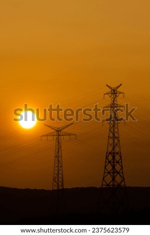 Sun disk at sunset. silhouette of high voltage line poles in orange sunset colors. Istanbul's energy transmission lines. Vertical photo. No people, nobody. Natural and traditional energy sources.